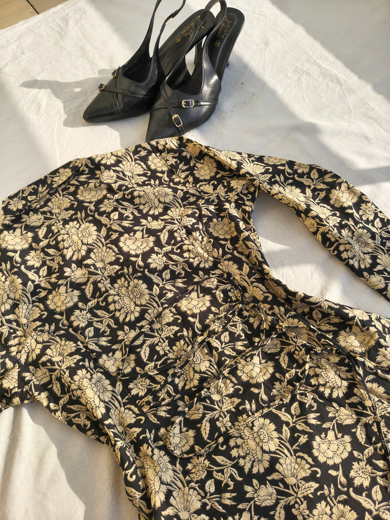 Black floral-patterned shirt with black high-heeled shoes on a white surface